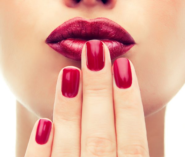Beautiful model shows red manicure on nails. Red lips .Luxury fashion style, manicure nail , cosmetics and makeup .